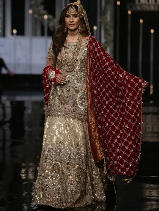 Seorang model mengenakan busana rancangan desainer Faike Karim selama Bridal Couture Week di Lahore, Minggu (9/12). Kreasi gaun pengantin yang ditampilkan didominasi kain sari yang menjadi ciri khas wanita Pakistan. (AP Photo/K.M. Chaudary)