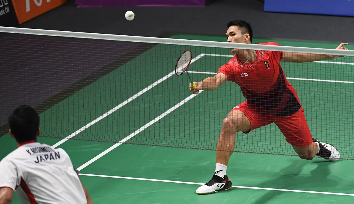 Pebulu tangkis Indonesia, Jonatan Christie (kanan) mengembalikan kok saat bertanding melawan Kenta Nishimoto asal Jepang dalam semifinal tunggal putra Asian Games 2018 di Jakarta, Senin (27/8). Jonatan menang lewat rubber game. (SONNY TUMBELAKA/AFP)