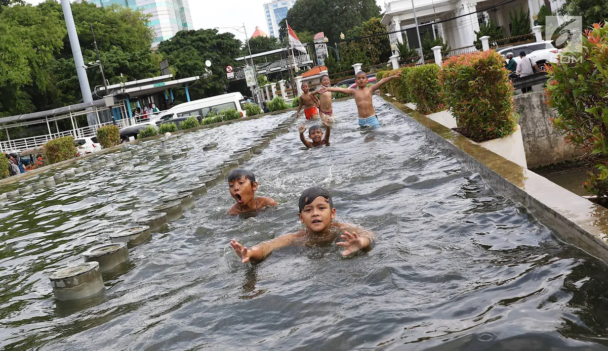 Anak-anak berenang di kolam air mancur penghias kawasan Pasar Baru, Jakarta, Selasa (29/1). Keterbatasan lahan bermain menyebabkan sebagian anak di Ibukota bermain tidak pada tempatnya, meskipun berbahaya bagi keselematan. (Liputan6.com/Immanuel Antonius)