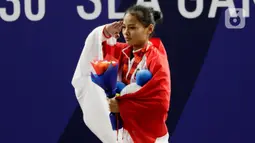 Lifter Windy Aisyah sikap hormat saat naik podium usai mendapatkan medali emas SEA Games 2019 cabang angkat besi nomor 49 kg di Stadion Rizal Memorial, Manila, Minggu (1/12/2019). Windy Aisyah meraih emas dengan total angkatan 104 kg. (Bola.com/M Iqbal Ichsan)