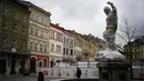 Pejalan kaki berjalan melewati patung yang dibungkus dengan plastik pelindung di dekat dewan kota di Lviv barat Ukraina, pada 5 Maret 2022. Warga kota Lviv membungkus semua patung untuk melindungi warisan sejarahnya dari kerusakan akibat serangan di tengah konflik Rusia-Ukraina. (Daniel LEAL/AFP)