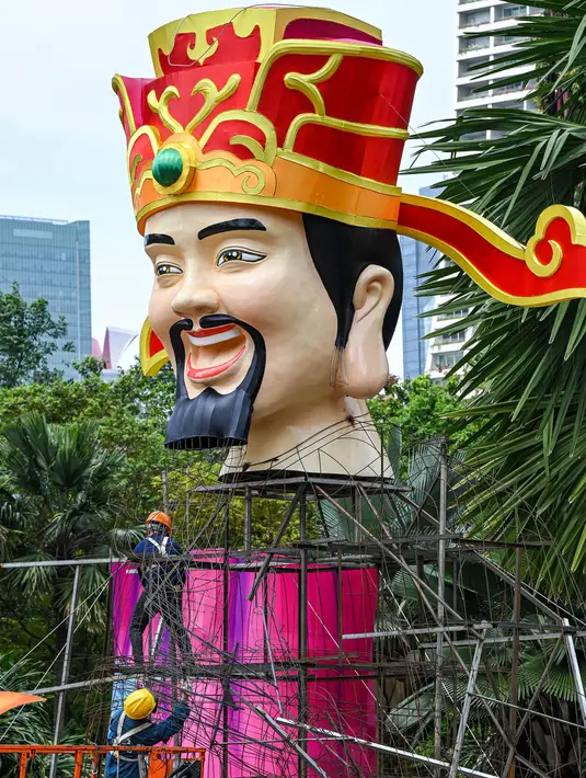 Para pekerja memasang struktur Dewa Keberuntungan sebagai persiapan untuk Tahun Baru Imlek mendatang di sekitar jalur pengamatan hutan Supertrees di Gardens by the Bay di Singapura pada 15 Januari 2024. (Roslan RAHMAN/AFP)