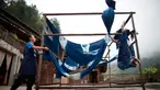 Dua orang perempuan menjemur kain di sebuah bengkel kerja di Desa Etnis Dong Fengdeng di Wilayah Rongjiang, Provinsi Guizhou, China pada 6 September 2020. Warga setempat memanfaatkan kondisi cuaca musim gugur yang mendukung untuk membuat kain tradisional kelompok etnis Dong. (Xinhua/Liu Xu)