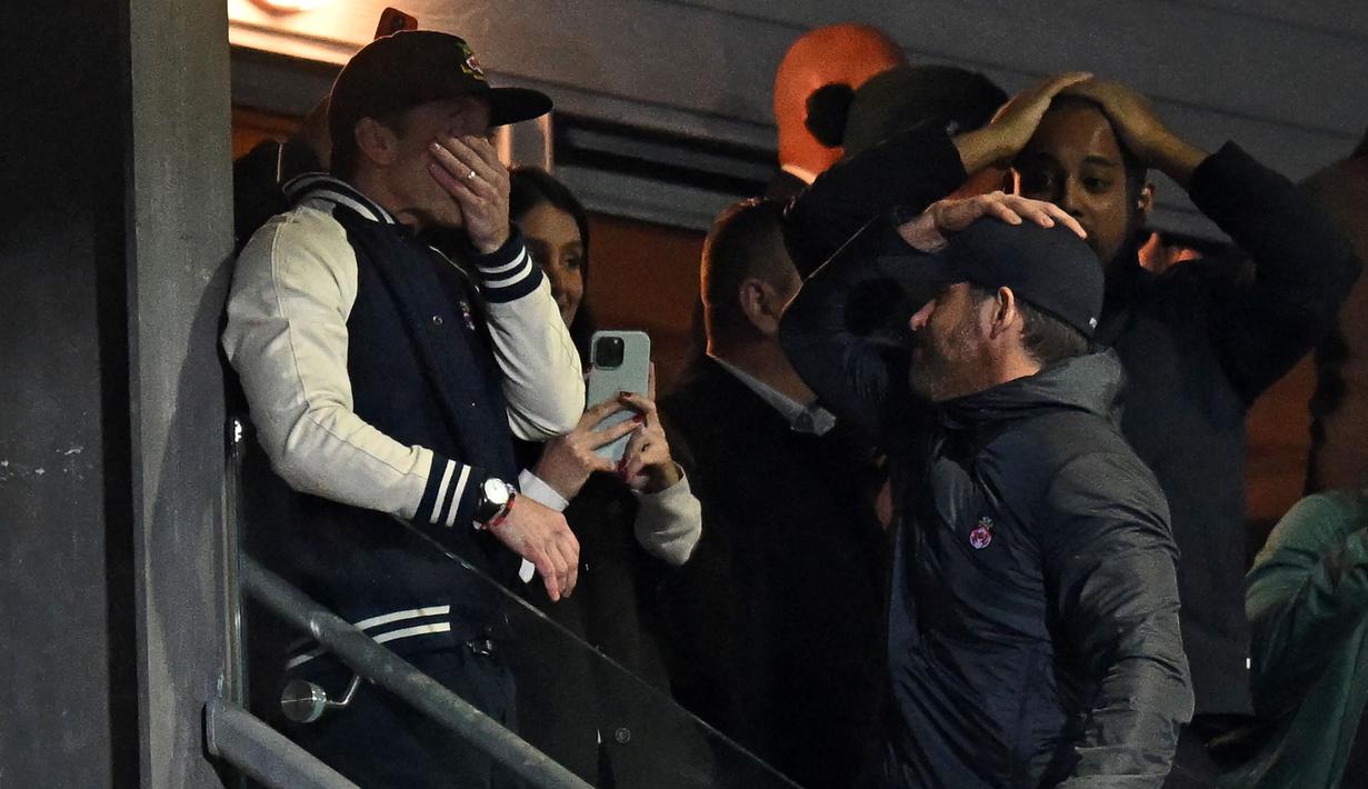 Aktor Hollywood, Ryan Reynolds (kanan) dan pemilik klub Wrexham, Rob McElhenney merayakan kemenangan timnya saat laga English National League antara Wrexham melawan Boreham Wood di Racecourse Ground Stadium, Wrexham, Wales, Sabtu (22/04/2023). Wrexham menang dengan skor 3-1 dan berhasil promosi ke Liga Dua Inggris. (AFP/Oli Scarff)