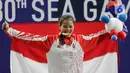 Lifter Windy Aisyah mengibarkan bendera usai mendapatkan medali emas SEA Games 2019 cabang angkat besi nomor 49 kg di Stadion Rizal Memorial, Manila, Minggu (1/12/2019). Windy Aisyah meraih emas dengan total angkatan 104 kg. (Bola.com/M Iqbal Ichsan)