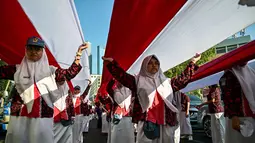 Pengibaran dan arak-arakan bendera Merah Putih di jalan-jalan menjadi simbol nasionalisme dan cinta tanah air. (Juni KRISWANTO/AFP)
