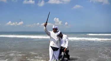 Seorang pria memegang keris saat sembahyang upacara Melasti di pantai Petitenget dekat Denpasar, di pulau resor Bali, Indonesia pada 19 Maret 2023. (AFP/SONNY TUMBELAKA)