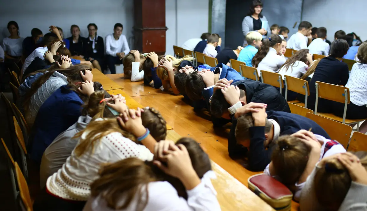 Anak-anak menutupi kepala dengan kedua tangan ketika latihan keamanan di Sekolah Nomor 8, Desa Sartana wilayah timur Ukraina, 2 Oktober 2018. Sebanyak 200.000 anak-anak masih bersekolah di kawasan yang rawan konflik itu. (Aleksey FILIPPOV/AFP)