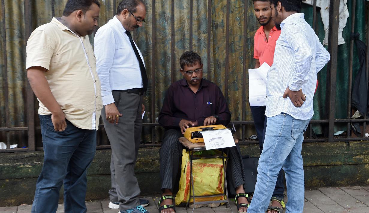 Sejumlah pria menunggu juru ketik menyelesaikan ketikannya di Mumbai, India (3/8). Sekitar 3.500 institut di negara bagian Maharashtra  yang masih menggunakan mesin tik manual akan diganti dengan komputer. (AFP Photo/Indranil Mukherjee)