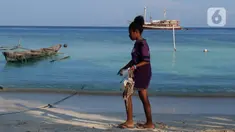 Seorang anak membawa sampah plastik yang ada di bibir pantai Desa Sawandarek, Raja Ampat, Papua Barat, Jumat (22/11/2019). Aksi membersihkan sampah plastik ini, digagas Carrie, aktivis asal Amerika Serikat,  yang sudah menetap di Indonesia selama 3 tahun. (Liputan6.com/Herman Zakharia)