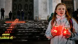 Seorang memegang lilin di depan Katedral Kristus Juruselamat Moskow, Rusia, Senin (12/2). Pesawat Saratov Airlines jatuh setelah lepas landas dari Bandara Domodedovo pada hari Minggu, 11 Februari 2018. (Maxim ZMEYEV / AFP)