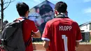 Fans berhenti untuk melihat mural manajer Liverpool Jurgen Klopp karya seniman Hugh Whitaker dari MurWalls di dekat stadion saat mereka tiba untuk menyaksikan laga pekan ke-38 Premier League melawan Wolverhampton Wanderers di Stadion Anfield, Minggu (19/5/2024). (Paul ELLIS / AFP)