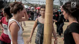 Warga negara asing bersiap mengikuti panjat pinang kolosal dalam rangka merayakan HUT ke-74 Kemerdekaan RI di Pantai Karnaval, Ancol, Jakarta, Senin (17/8/2019). Sebanyak 174 batang pinang dengan beragam hadiah disediakan dalam lomba yang diikuti ratusan warga itu. (Liputan6.com/Faizal Fanani)