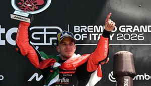 Pemenang dari Tim Aprilia Racing, Marco Bezzecchi, merayakan kemenangannya di podium dengan trofi setelah Grand Prix MotoGP Italia di sirkuit Mugello, di Mugello, dekat Florence, pada 31 Mei 2026. (Andreas SOLARO/AFP)