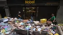 Ribuan buku rusak terlihat di jalan setelah hujan lebat membanjiri toko buku di Petropolis, Brasil, 19 Februari 2022. Sebanyak 136 jenazah telah diidentifikasi hingga kini, menurut pejabat pertahanan sipil, di kota wisata yang biasanya indah, sekitar 60 km utara Rio de Janeiro. (MAURO PIMENTEL/AFP)