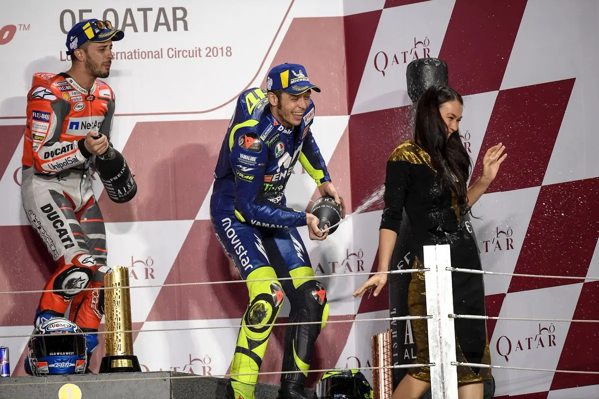 Pembalap Movistar Yamaha, Valentino Rossi saat merayakan podium MotoGP Qatar 2018 bersama Marc Marquez dan Andrea Dovizioso. (KARIM JAAFAR / AFP)