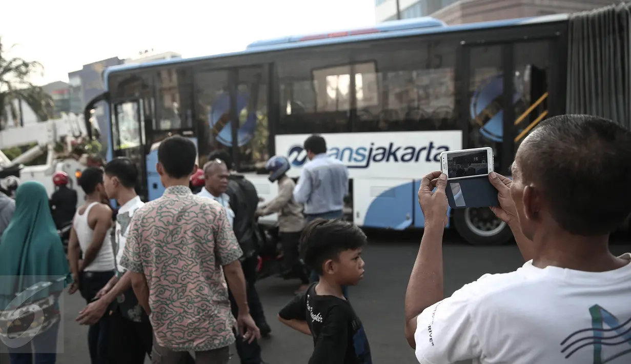 Warga mengambil gambar bus TransJakarta usai ditabrak kereta api Senja Utama Solo di perlintasan kereta Mangga Dua, Jakarta, Kamis (19/5). Selain menabrak bus TransJakarta, KA Senja Utama Solo juga menabrak mobil Avanza. (Liputan6.com/Faizal Fanani)