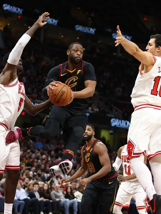 Aksi Dwyane Wade #9 melompat sambil memberikan umpan saat dikepung dua pemain  Chicago Bulls pada laga NBA basketball game di Quicken Loans Arena, Cleveland, (21/12/2017). Cleveland menang 115-112. (Gregory Shamus/Getty Images/AFP)