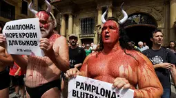 Sejumlah aktivis membasahi wajahnya dengan darah palsu saat aksi menolak festival San Fermin di Pamplona, Spanyol, (5/7).Mereka membawa poster yang bertuliskan "Pamplona: lautan darah bagi banteng." (REUTERS/Susana Vera)