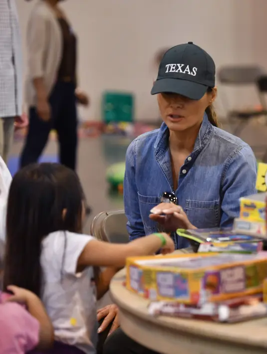 Ibu Negara AS, Melania Trump berbincang dengan seorang anak korban Badai Harvey di NRG Center di Houston (2/9). (AFP Photo/Nicholas Kamm)
