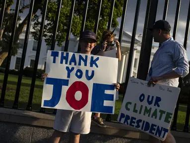 Hugh Kieve (10) memegang papan bertuliskan 'Terima Kasih Joe' bersama saudara perempuannya Margot dan ayahnya David Kieve di sepanjang Pennsylvania Avenue di depan Gedung Putih, Minggu (21/7/2024). (SAMUEL CORUM / AFP)