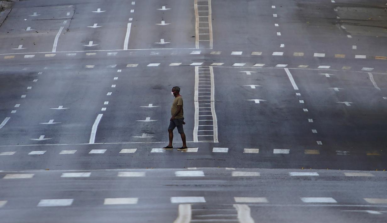 Seorang pria yang mengenakan masker berjalan di jalanan kosong saat penerapan jam malam di Havana, Kuba, Selasa (1/9/2020). Otoritas Kuba menerapkan lockdown selama 15 hari di Havana untuk keluar dari penularan COVID-19 tingkat rendah tetapi terus-menerus. (AP Photo/Ramon Espinosa)