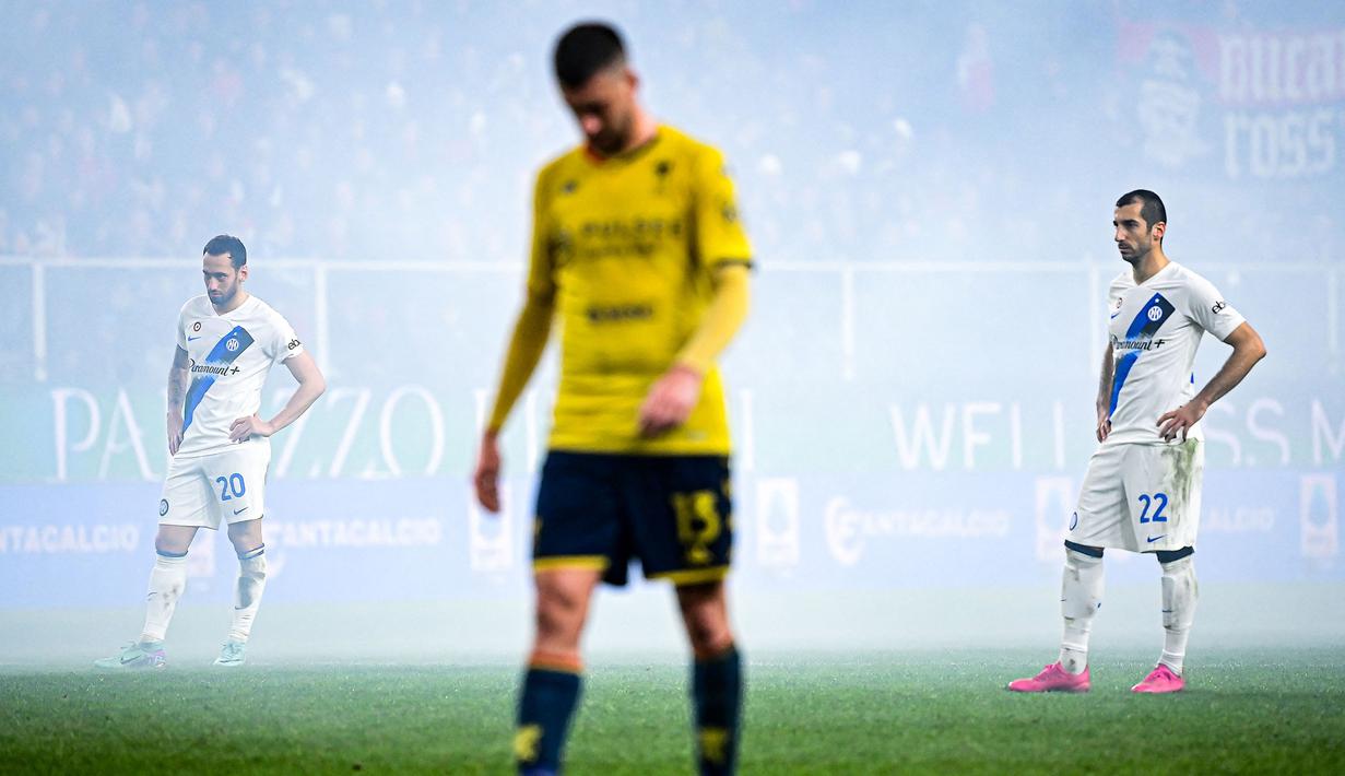 Pemain Inter Milan, Hakan Calhanoglu (kiri) dan Henrikh Mkhitaryan terlihat dalam kepulan asap saat laga lanjutan Liga Italia 2023/2024 melawan Genoa di Stadion Luigi Ferraris, Genoa, Italia, Sabtu (30/12/2023) dini hari WIB. (AFP/Piero Cruciatti)