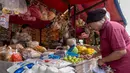 Seorang pembeli (kanan) sedang memilih bahan makanan mentah di sebuah warung pasar tradisional di Jakarta pada Rabu 3 Juni 2026. (BAY ISMOYO/AFP)