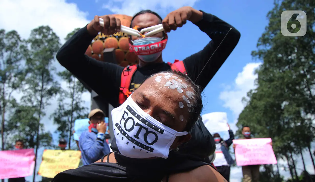 Seorang jurnalis melakukan aksi teatrikal saat aksi solidaritas di kawasan Tugu Adipura, Kota Tangerang, Rabu (31/3/2021). Mereka menuntut pihak berwenang mengusut tuntas oknum pelaku kekerasan terhadap wartawan Tempo, Nurhadi dan kasus kekerasan jurnalis lainnya. (Liputan6.com/Angga Yuniar)