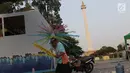Pekerja menyelesaikan pembuatan kembang hiasan untuk diletakkan di atas kendaraan hias di kawasan Monas, Jakarta, Jumat (28/6/2019). Kendaraan hias tersebut dipersiapkan untuk Jakarnaval 2019 yang menjadi  perayaan HUT ke-492 DKI Jakarta, Minggu (30/6). (Liputan6.com/Helmi Fithriansyah)