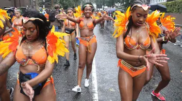 Penari karnaval menari di tengah hujan selama parade hari pertama Karnaval Notting Hill di London barat, Minggu (26/8). Karnaval Notting Hill yang merupakan pawai jalanan terbesar di Eropa diadakan setiap tahun sejak tahun 1966. (AFP/Daniel LEAL-OLIVAS)