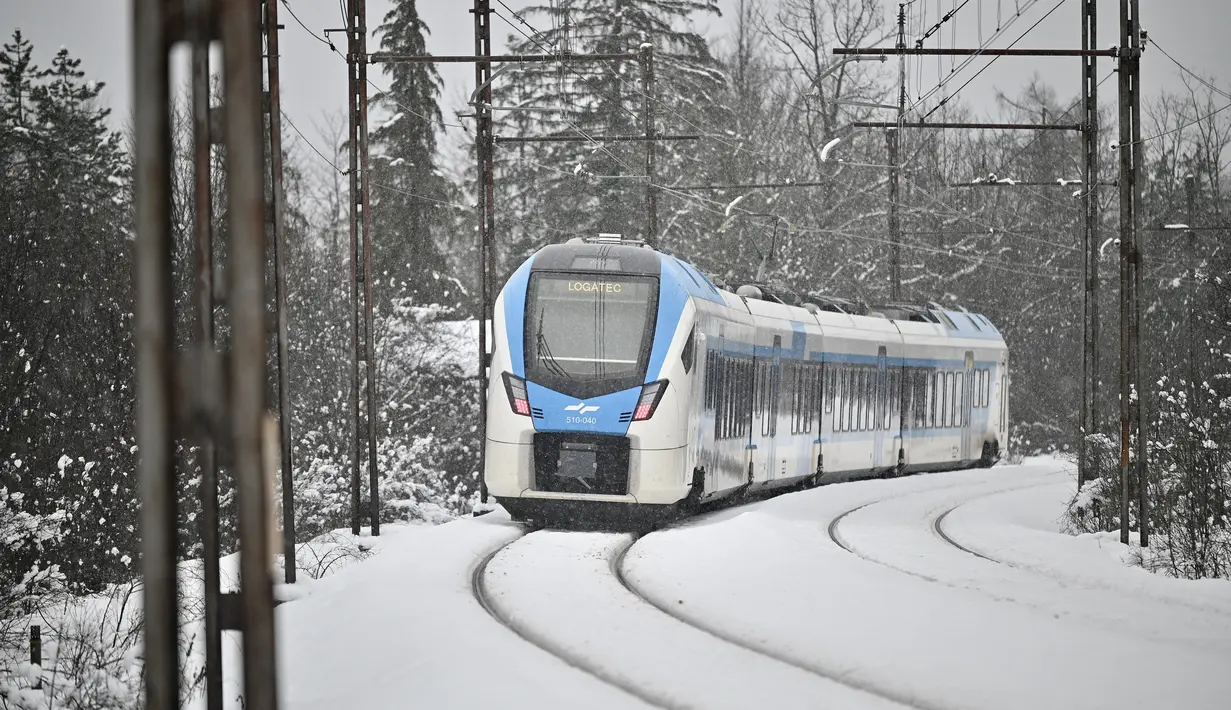 Sebuah kereta penumpang melewati hujan salju di dekat kota Planina, Slovenia, pada Senin (23/1/2023). Hujan salju lebat dan angin kencang menghambat lalu lintas dan menyebabkan pemadaman listrik di seluruh Slovenia. (Jure Makovec / AFP)
