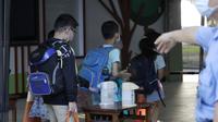 Siswa sekolah dasar mengenakan masker untuk melindungi diri dari penyebaran COVID-19 dan dan mendisinfeksi saat tiba di sekolah di Taipei, Taiwan, Rabu (1/9/2021). Seluruh sekolah di Taiwan kembali dibuka untuk tahun ajaran baru setelah ditutup akibat pandemi COVID-19. (AP Photo/Chiang Ying-ying)