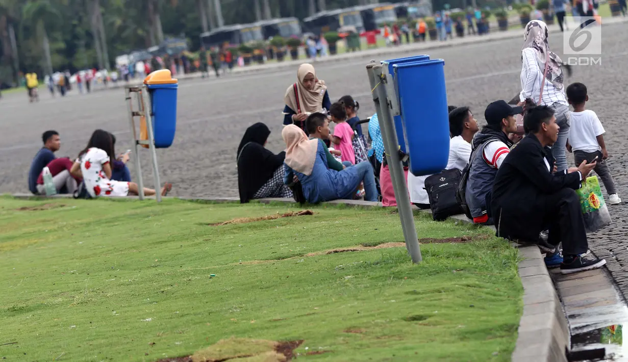 Warga duduk beristirahat di kawasan Monumen Nasional, Jakarta, Jumat (19/4). Libur panjang perayaan Paskah 2019 dimanfaatkan warga untuk berwisata di kawasan Monumen Nasional. (Liputan6.com/Helmi Fithriansyah)