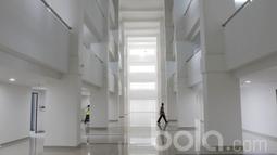 Seorang pekerja melintas di dalam pembangunan wisma Atlet di Kemayoran. Nilai kontrak pembangunan wisma Atlet Kemayoran ini mencapai Rp 3,4 triliun. (Bola.com/M Iqbal Ichsan)