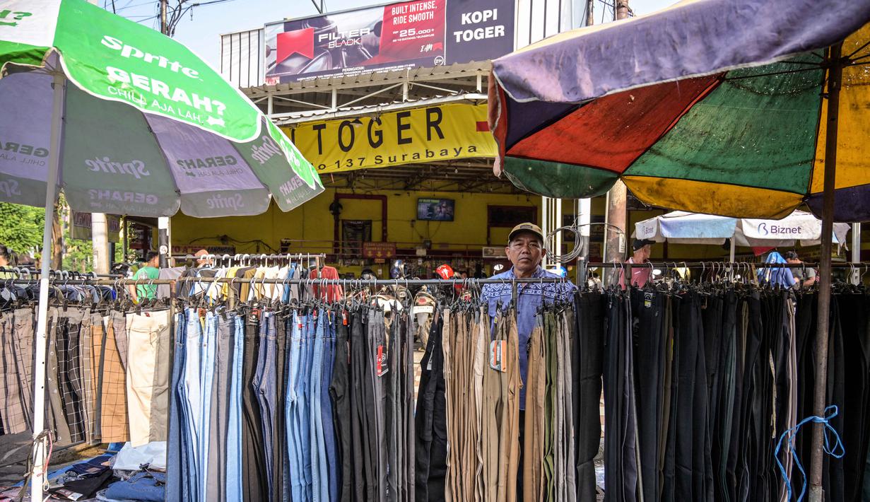 Seorang pedagang menata celana panjang sambil menunggu pelanggan pakaiannya di salah satu ruas jalan, Surabaya, Jawa Timur, pada Minggu 19 April 2026. Badan Pusat Statistik (BPS) Republik Indonesia akan melaksanakan Sensus Ekonomi 2026 (SE2026). (JUNI KRISWANTO/AFP)