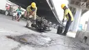 Petugas menambal lubang pada jalan yang rusak di kawasan Jatinegara, Jakarta, Kamis (7/2). Musim hujan yang mengguyur Jakarta selama beberapa waktu terakhir meninggalkan kerusakan pada sejumlah ruas jalan di Ibukota. (Liputan6.com/Immanuel Antonius)