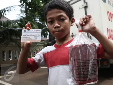 Seorang anak memperlihatkan daging beku yang baru dibeli pada operasi pasar murah di Kantor Kecamatan Matraman, Jakarta, Senin (27/6). Operasi pasar ini menjual daging sapi & ayam murah kepada pemegang KJP Sekolah Dasar (SD). (Liputan6.com/Faizal Fanani)