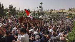 Pelayat Palestina membawa peti mati jurnalis Al-Jazeera Shireen Abu Akleh yang tewas tertembak, selama prosesi pemakamannya dari gereja menuju pemakaman, di Yerusalem, pada 13 Mei 2022. Shireen Abu Akleh yang merupakan jurnalis senior berusia 51 tahun itu terkena tembakan di kepala ketika meliput serangan Israel di Kota Jenin, di wilayah Tepi Barat yang diduduki pada 11 Mei 2022 lalu. (RONALDO SCHEMIDT / AFP)