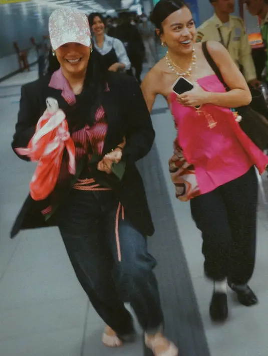 Tara Basro tampil dengan sentuhan preppy yang edgy dan effortless. Dalam foto pertama, ia mengenakan blazer hitam yang dipadukan dengan kemeja bergaris merah dan celana jeans.  Aksen topi pink berkilau memberikan sentuhan playful yang unik pada look-nya. Dengan make-up minimalis dan rambut panjang tergerai, Tara tampak percaya diri dan bold. [@taabasro].
