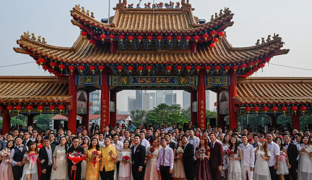 Pasangan pengantin baru keturunan Tionghoa  berfoto bersama seusai acara pernikahan massal di Kuil Thean Hou, Kuala Lumpur, Senin (9/9/2019). Upacara pernikahan massal diadakan untuk 99 pasangan pada hari kesembilan bulan kesembilan yang dianggap sebagai tanggal keberuntungan. (Mohd RASFAN / AFP)