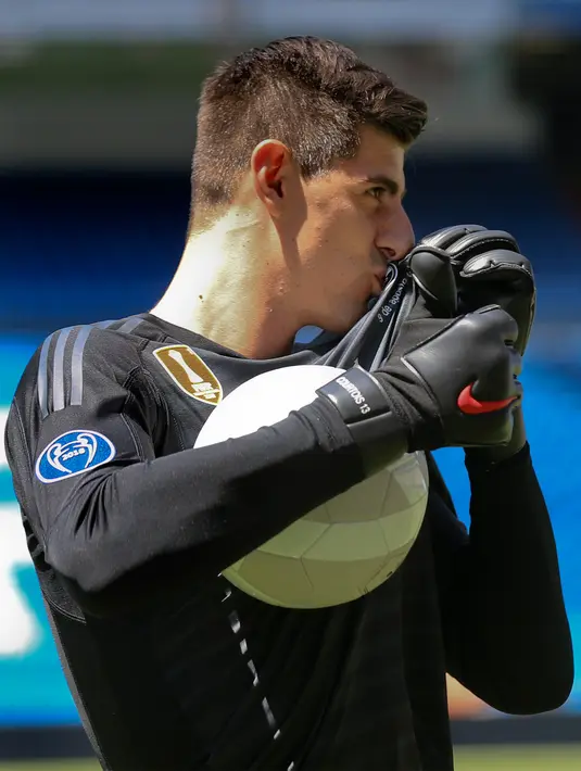 Kiper asal Belgia Thibaut Courtois mencium logo jersey Real Madrid selama presentasi dirinya menjadi pemain Real Madrid di stadion Santiago Bernabeu (9/8). Courtois resmi didapatkan Madrid dari Chelsea hingga musim 2023/24. (AP Photo/Andrea Comas)