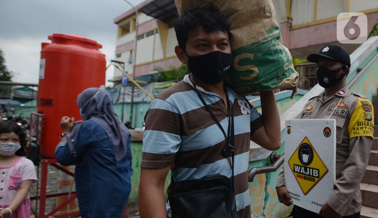 Petugas Polres Jakarta Timur melakukan sosialisasi dan membagikan masker di Pasar Palmeriam, Matraman, Selasa (9/2/2021). Kegiatan itu dilakukan sebagai upaya meningkatkan kesadaran masyarakat akan pentingnya penerapan protokol kesehatan untuk menekan penyebaran Covid-19. (merdeka.com/Imam Buhori)
