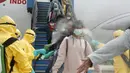 Petugas menyemprotkan cairan disinfektan ke WNI yang dievakuasi dari Wuhan, China saat tiba di bandara internasional Hang Nadim, Batam, Minggu (2/2/2020). Sebanyak 245 WNI di Wuhan dievakuasi ke Indonesia terkait merebaknya virus corona di kota tersebut. ((Photo by Handout/Indonesian Embassy/AFP)