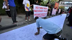 Seorang warga membubuhkan tanda tangan mendukung pemakzulan Gubernur DKI Basuki Tjahaja Purnama alias Ahok di Bundaran HI, Jakarta, Minggu (22/2/2015). Mereka melakukan aksi ini karena kebijakan Ahok dinilai tak pro-rakyat. (Liputan6.com/Faizal Fanani)