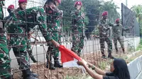 Buruh wanita Eva menyerahkan bendera merah putih ke anggota TNI di sela demo. (Ady Anugrahadi/Liputan6.com).