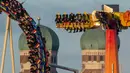 Pengunjung menaiki roller coaster di dekat Katedral Bunda Maria selama festival bir Oktoberfest di Munich, 24 September 2018. Festival ini merupakan salah satu acara paling terkenal di Jerman sejak tahun 1800an. (AFP/dpa/Peter Kneffel/ Germany OUT)