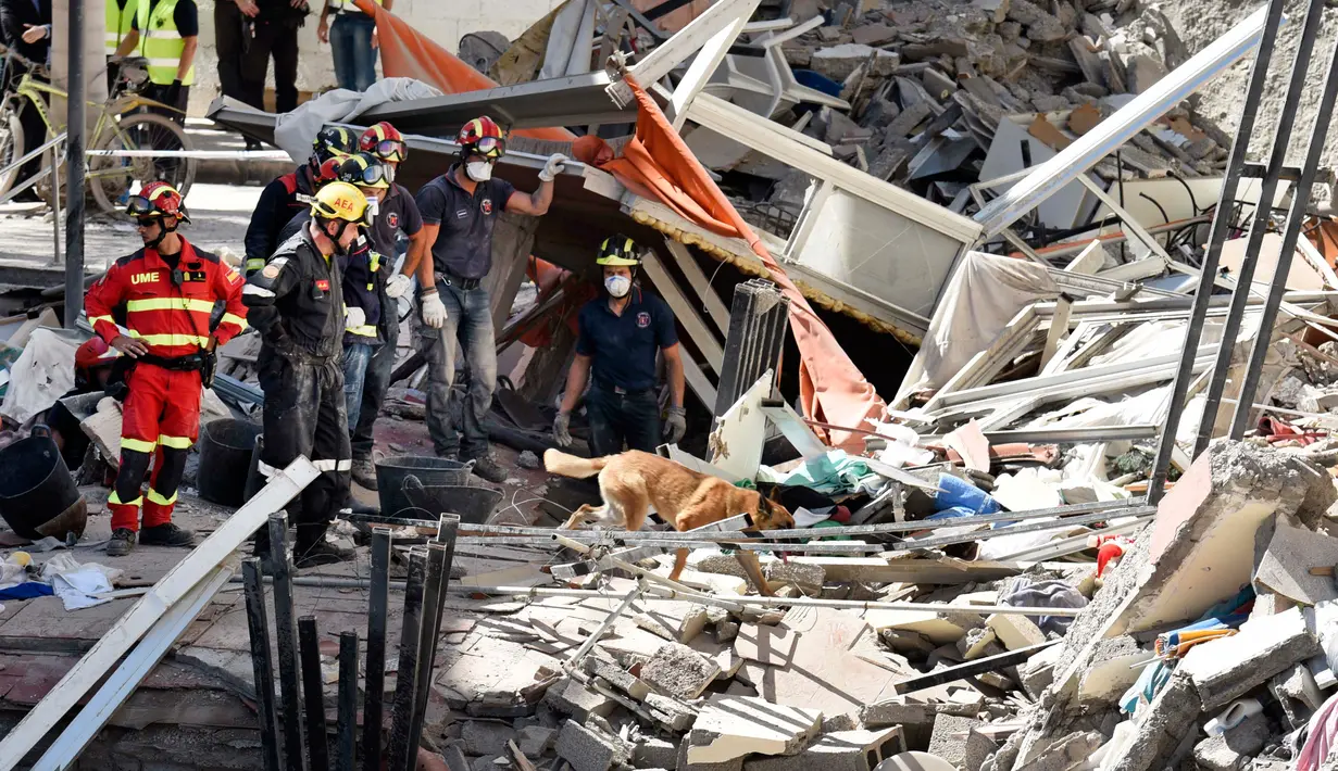 Tim penyelamat dibantu anjing pelacak mencari para korban di puing-puing gedung apartemen lima lantai yang runtuh di kota wisata Los Cristianos, Tenerife, Spanyol, Kamis (14/4). 9 orang terjebak di dalam reruntuhan gedung tersebut. (Desiree MARTIN/AFP)