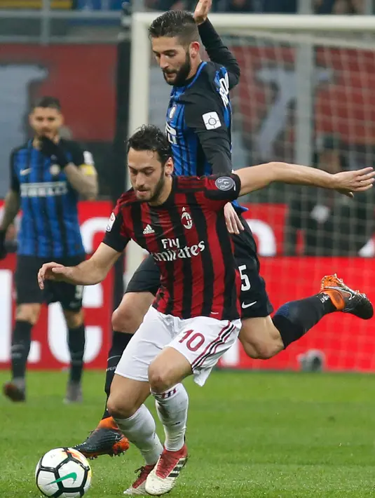 Pemain AC Milan Hakan Calhanoglu berebut bola dengan pemain Inter Milan Roberto Gagliardini saat pertandingan Liga Italia di stadion San Siro, Milan (4/4). (AP Photo / Antonio Calanni)
