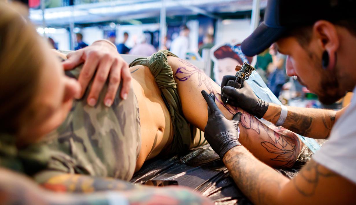 Seorang seniman mentato badan pengunjung wanita dalam acara edisi keempat Montreux Tattoo Convention di Montreux, Swiss  (22/9). Lebih 150 seniman tato dari 22 negara berkumpul dalam acara tersebut. (Valentin Flauraud/Keystone via AP)